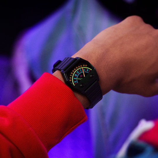 A close-up lifestyle shot of a person's wrist, wearing a black Sector wristwatch with a glowing lume display.