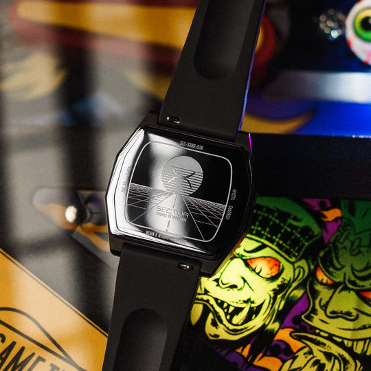 caseback of the sector watch with vaporwave engraving against a pinball machine background