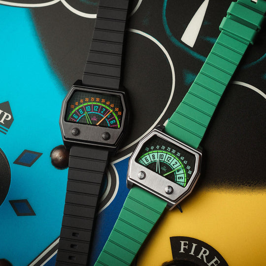 Two retro-style wristwatches with colorful analog gauges, one with a black strap and one with a green textured strap, displayed on a vibrant, graphic-patterned background.