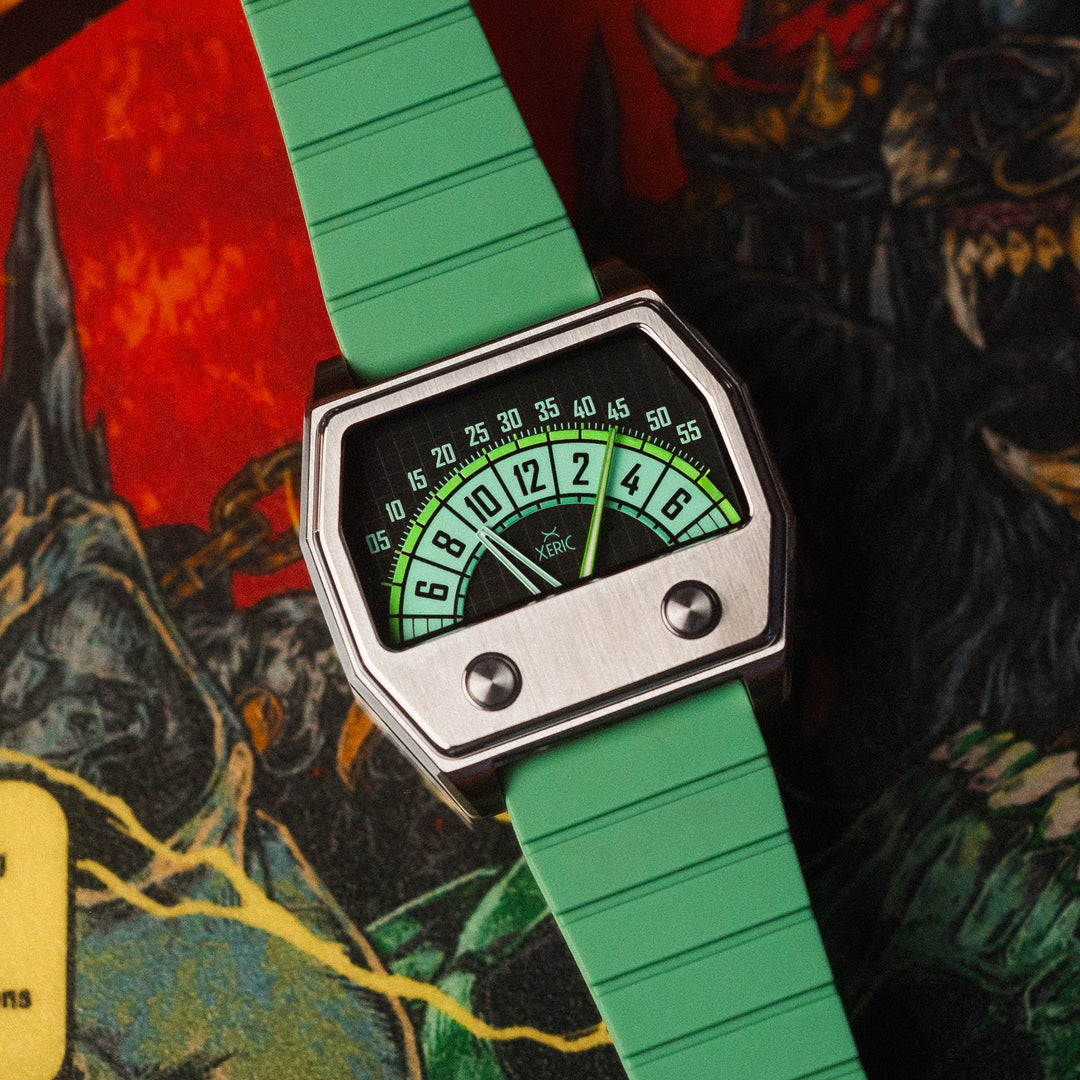 A retro-futuristic wristwatch with a bright green textured strap, a silver-toned geometric case, and a dial featuring green and black sections with white numbers, displayed diagonally over a colorful monster-themed illustration.